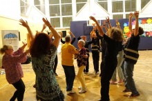 Para seniorów tańczy w kole utworzonym przez młodzież
