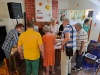 Seniorzy stoją przy stole oglądając przedmioty związane z folklorem mazowieckim