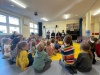 Grupa dzieci z przedszkola słucha bajek czytanych przez seniorów