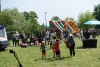 Dzieci i dorośli spacerujący w trakcie pikniku - w tle dmuchane zjeżdzalnie dla dzieci